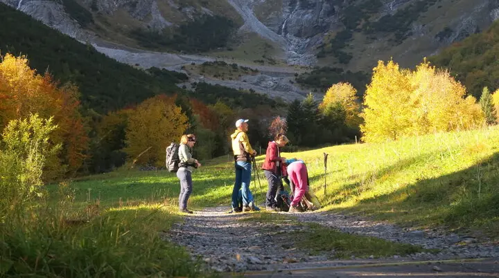 Wanderer mit Rucksäcken auf einem Weg in herbstlicher Berglandschaft mit bunten Bäumen und Felsen im Hintergrund. | © DAV-FN / I. Eichenberg