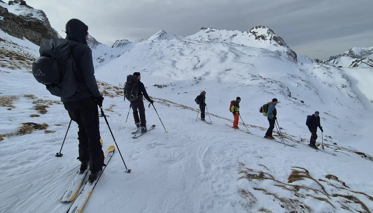 Gruppe von Skifahrern mit Rucksäcken auf schneebedecktem Berghang unter bewölktem Himmel | © DAV-Fn / R. Lebedeff