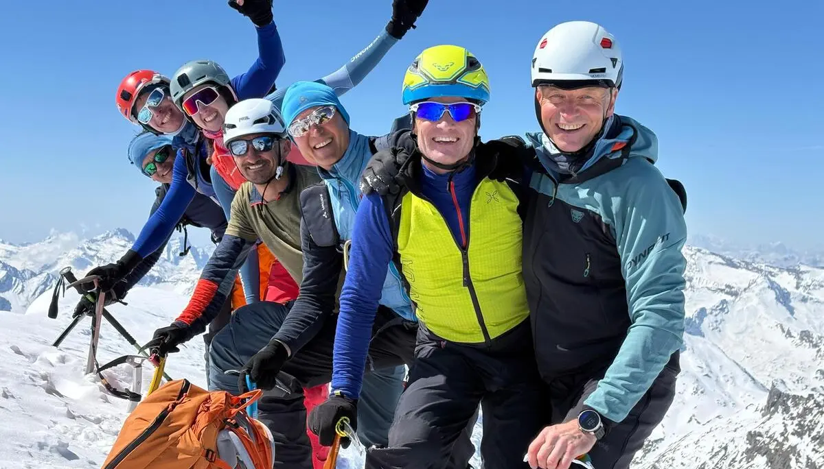 Gruppe von Bergsteigern mit Helmen und Kletterausrüstung auf schneebedecktem Gipfel mit Bergpanorama | © DAV-FN / R. Gersten