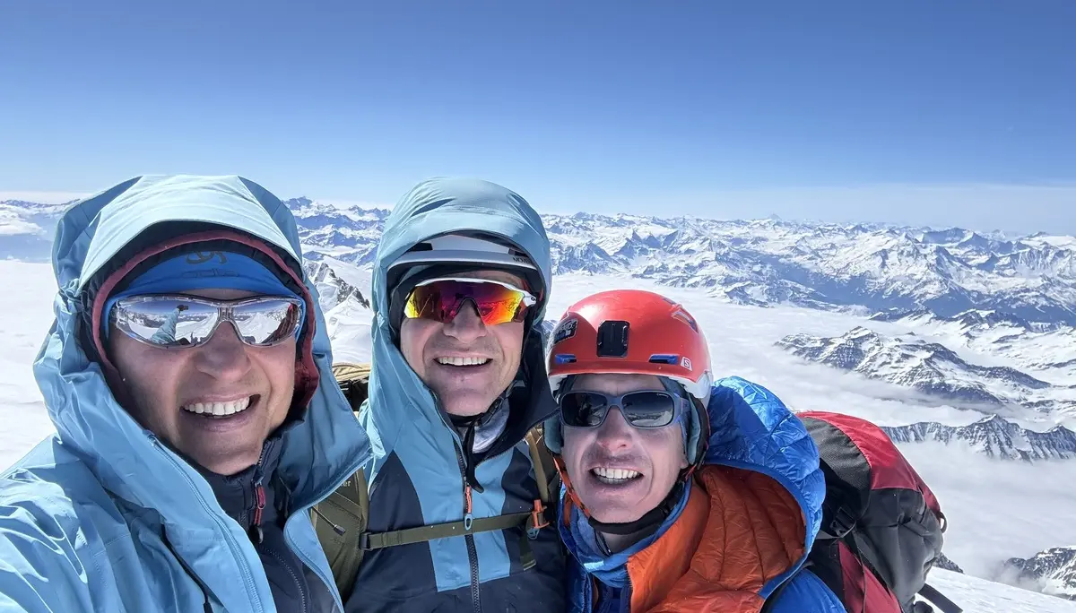 Drei Personen in Winterjacken und Helmen stehen auf einem schneebedeckten Berg mit Bergpanorama im Hintergrund | © DAV-FN / R. Gersten