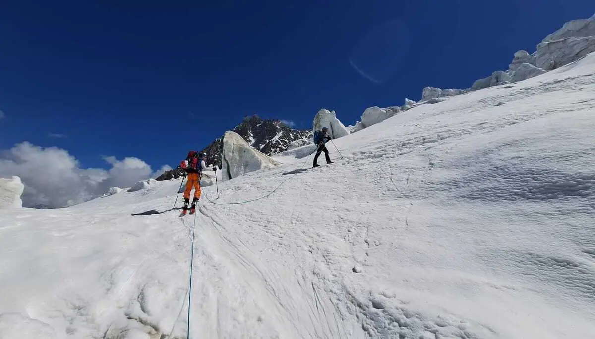 Zwei Bergsteiger mit Kletterausrüstung steigen an einem schneebedeckten Hang auf, verbunden durch ein Seil | © DAV-FN / R. Gersten