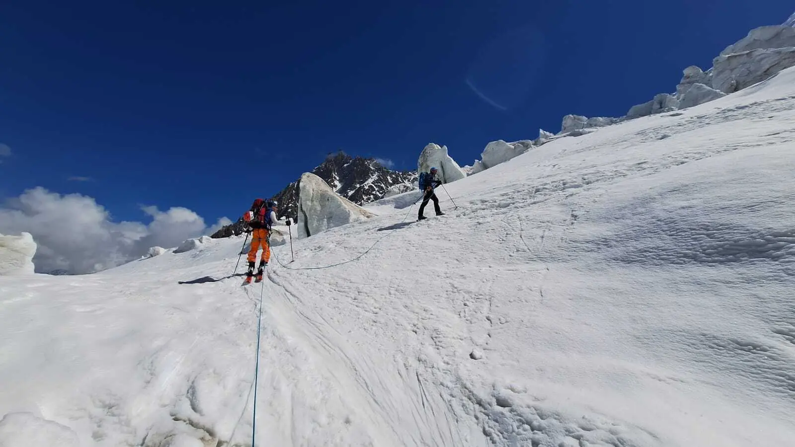 Zwei Bergsteiger mit Kletterausrüstung steigen an einem schneebedeckten Hang auf, verbunden durch ein Seil | © DAV-FN / R. Gersten