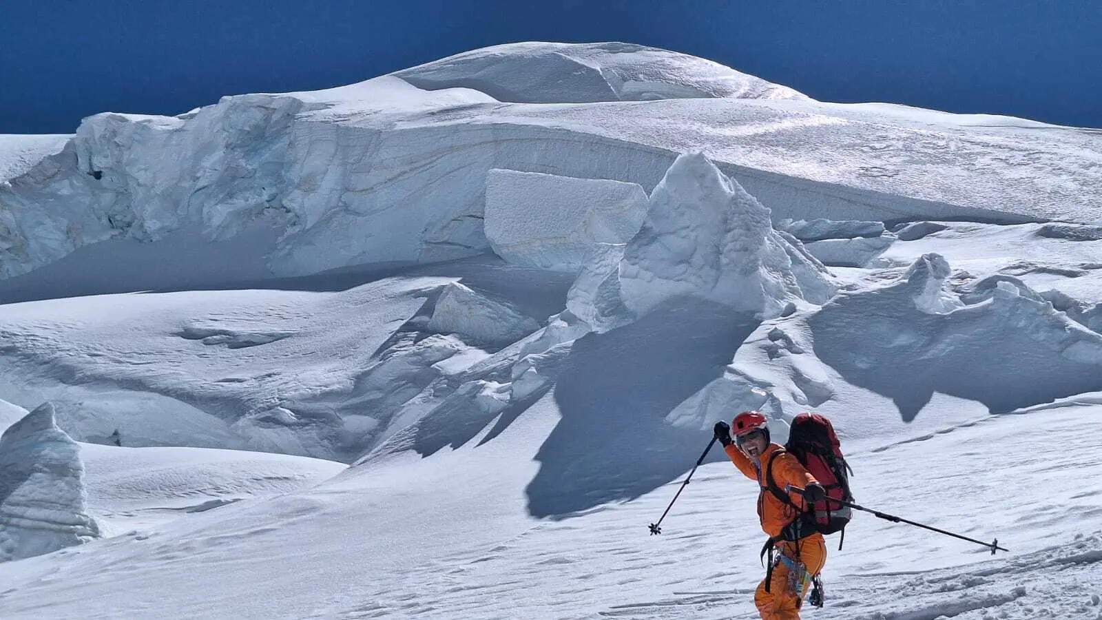 Bergsteiger mit rotem Rucksack und oranger Kleidung bei Abfahrt auf schneebedecktem Gletscher | © DAV-FN / R. Gersten