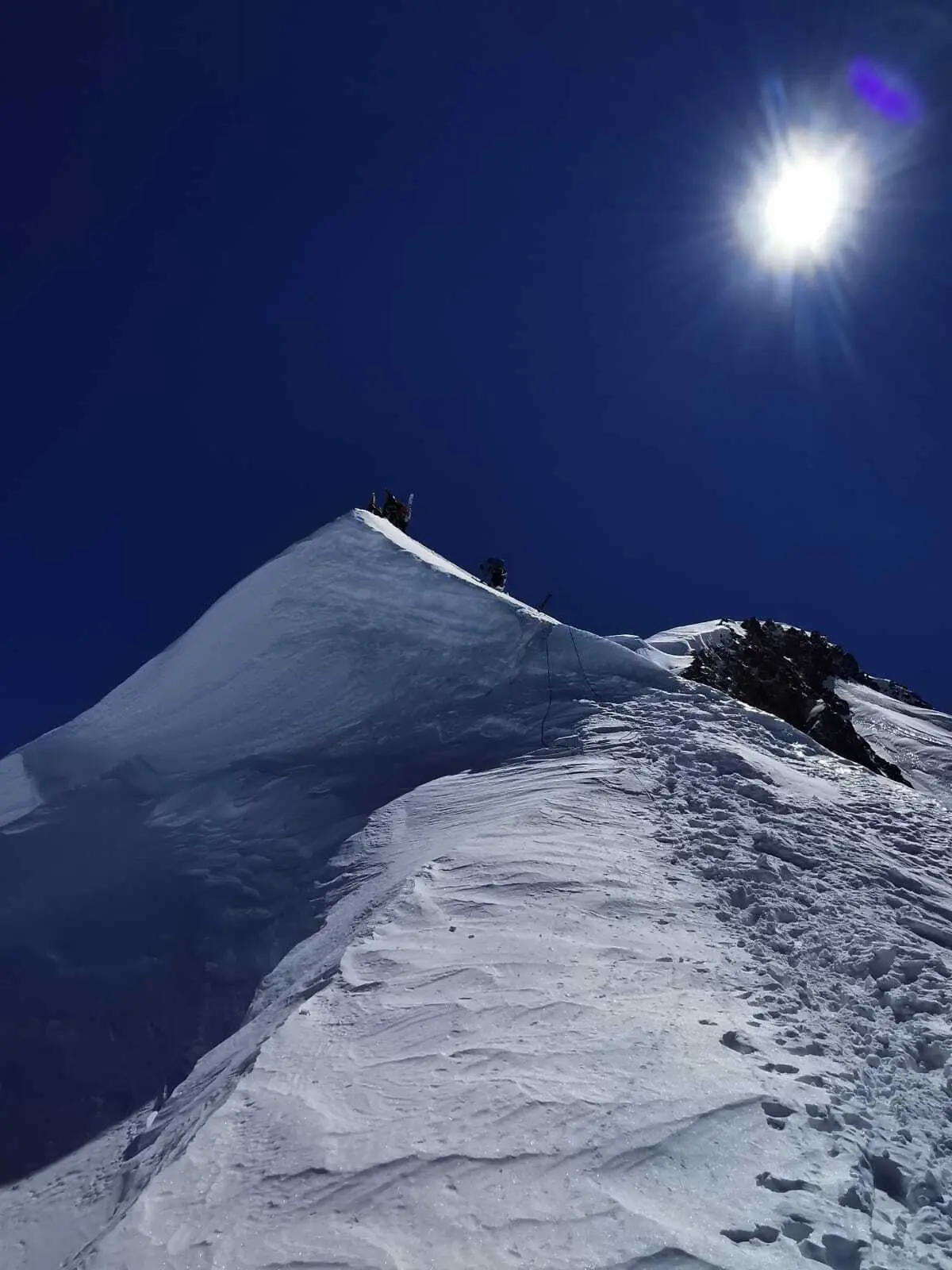 Bergsteiger auf schneebedecktem Grat unter strahlend blauem Himmel mit greller Sonne | © DAV-FN / R. Gersten
