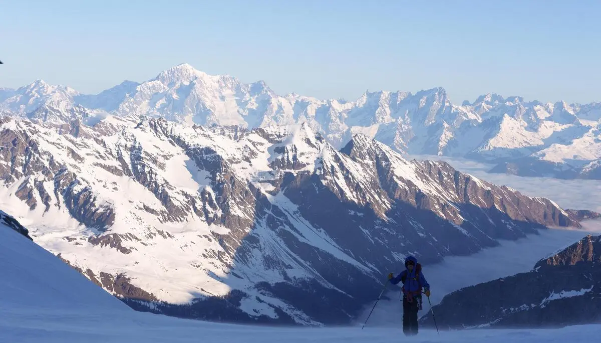 Berglandschaft mit schneebedeckten Gipfeln und einer einzelnen Person mit Skistöcken im Vordergrund | © DAV-FN / R. Gersten