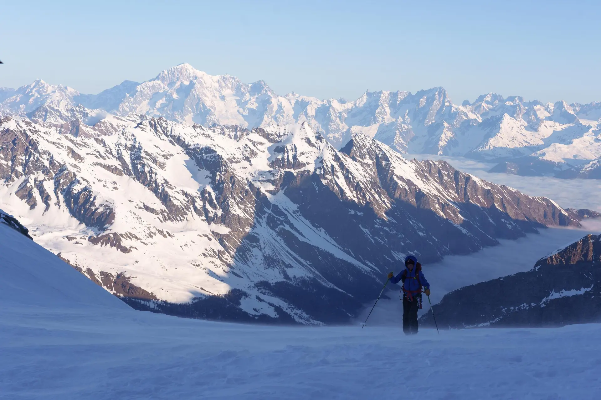 Berglandschaft mit schneebedeckten Gipfeln und einer einzelnen Person mit Skistöcken im Vordergrund | © DAV-FN / R. Gersten