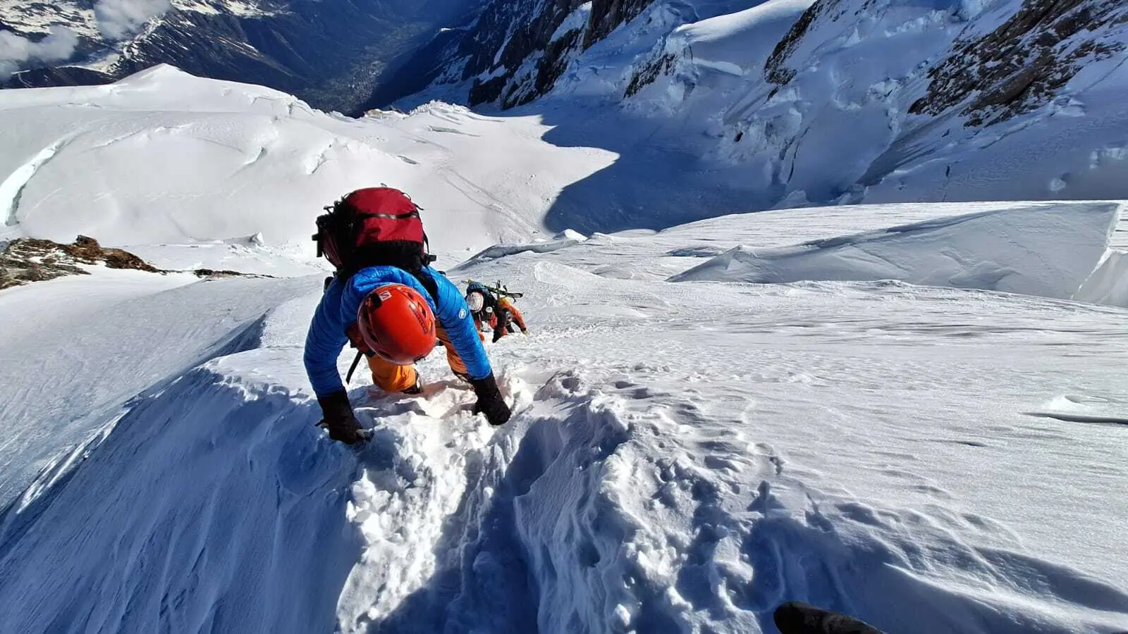 Bergsteiger mit rotem Helm und blauem Oberteil klettert steilen schneebedeckten Hang hinab | © DAV-FN / R. Gersten
