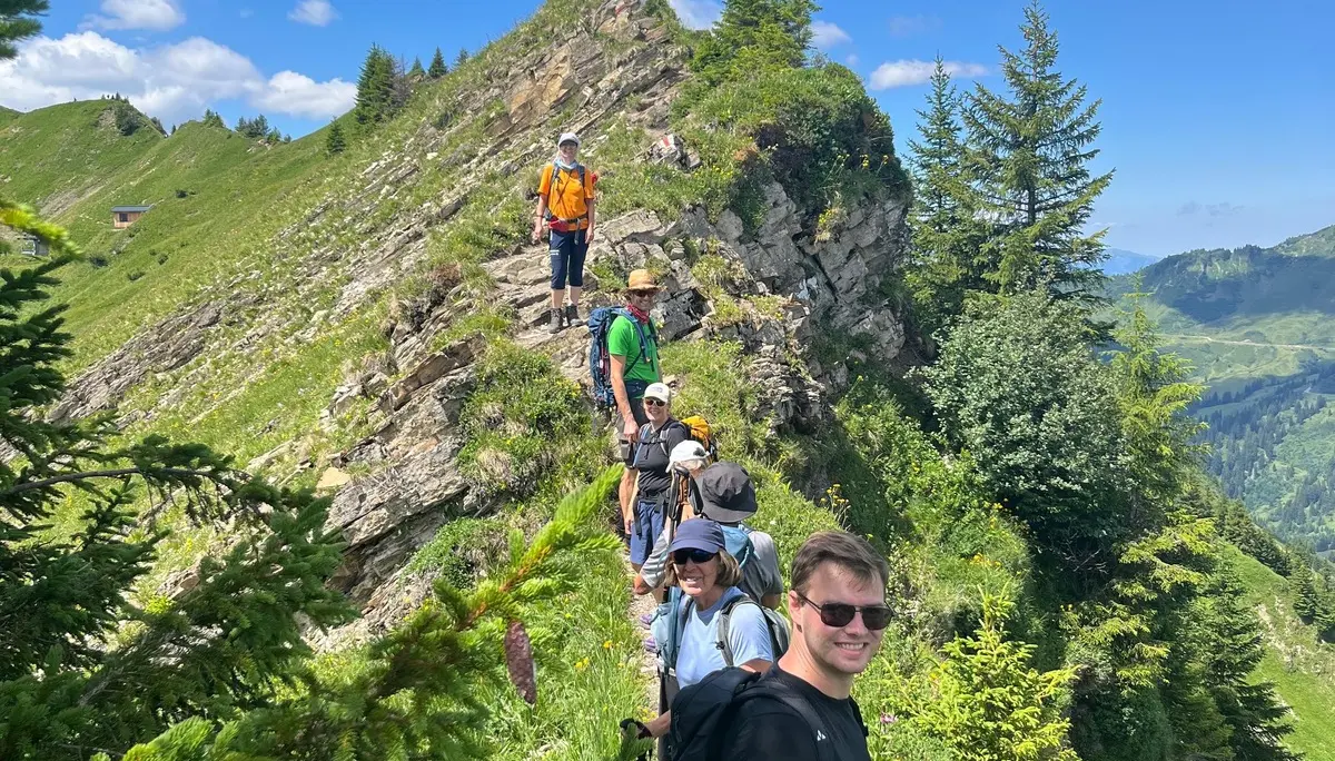 Gruppe von Wanderern auf schmalem Bergkamm mit grüner Vegetation unter blauem Himmel | © DAV - FN / N. Böttcher