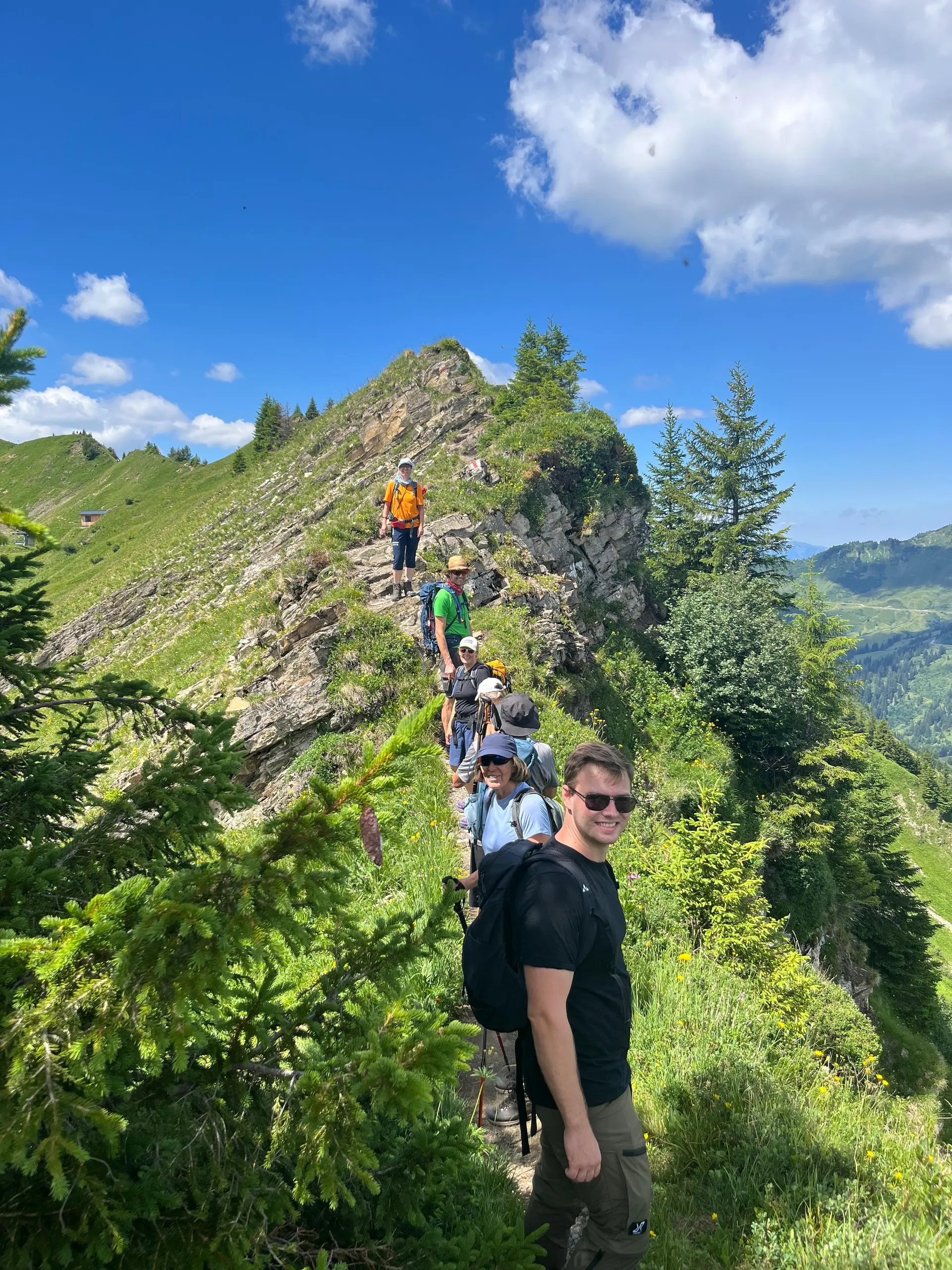 Gruppe von Wanderern auf schmalem Bergkamm mit grüner Vegetation unter blauem Himmel | © DAV - FN / N. Böttcher