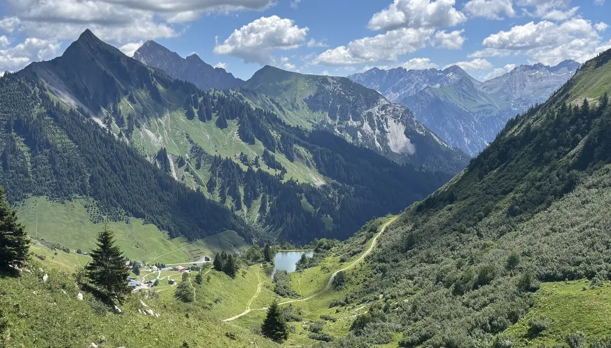 Berglandschaft mit bewaldeten Hängen, einem kleinen See im Tal und einem Wanderweg | © DAV - FN / A. Schech
