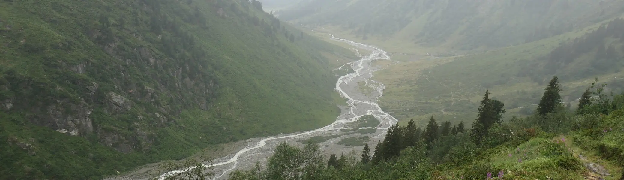 Bergtal mit grün bewachsenen Hängen und einem sich schlängelnden Fluss im Nebel | © DAV - FN / S. Dischler