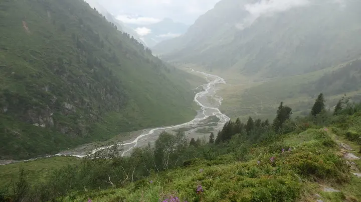 Bergtal mit grün bewachsenen Hängen und einem sich schlängelnden Fluss im Nebel | © DAV - FN / S. Dischler