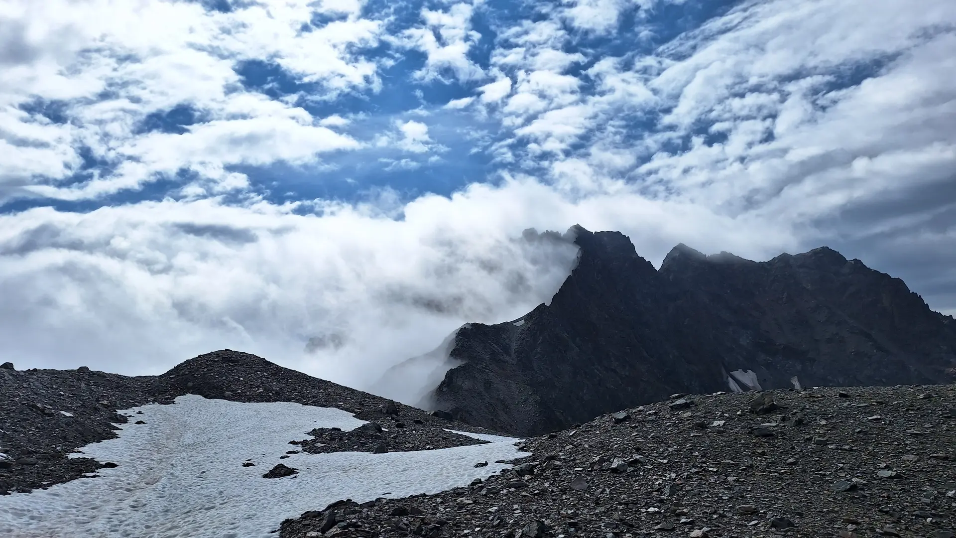 Berggipfel mit Wolken und Schneefeldern unter einem bewölkten Himmel | © Dav-Fn / R. Huber