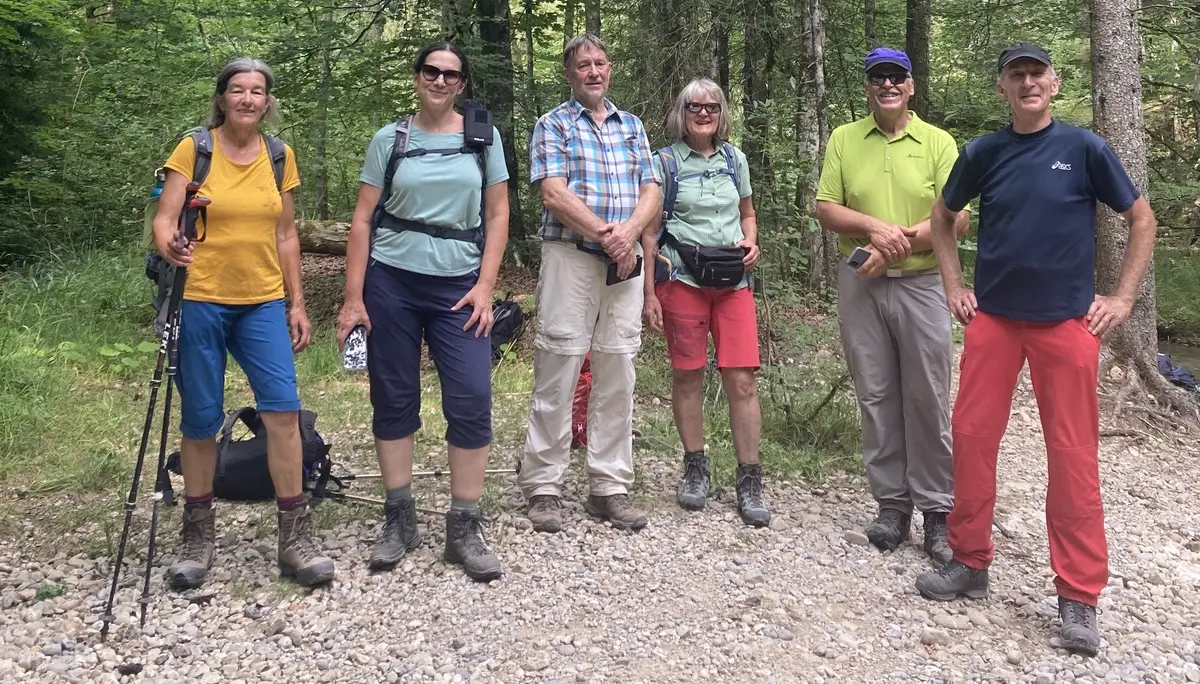 Sechs Personen in Wanderkleidung stehen auf einem Waldweg vor hohen Bäumen | © DAV-FN / K. Seuster