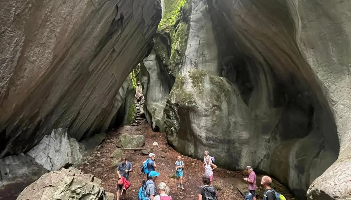 Gruppe von Wanderern steht in einer hohen, engen Felsenschlucht mit moosbedeckten Wänden | © DAV - FN / K. Seuster