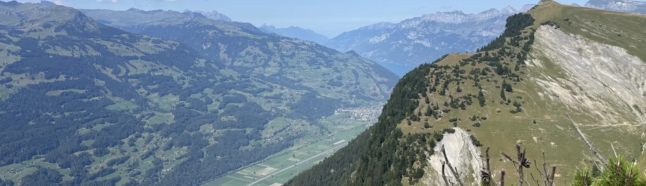 Berglandschaft mit bewaldeten Hängen, steilen Felswänden und einem Tal im Hintergrund unter blauem Himmel | © DAV - FN / A. Schech