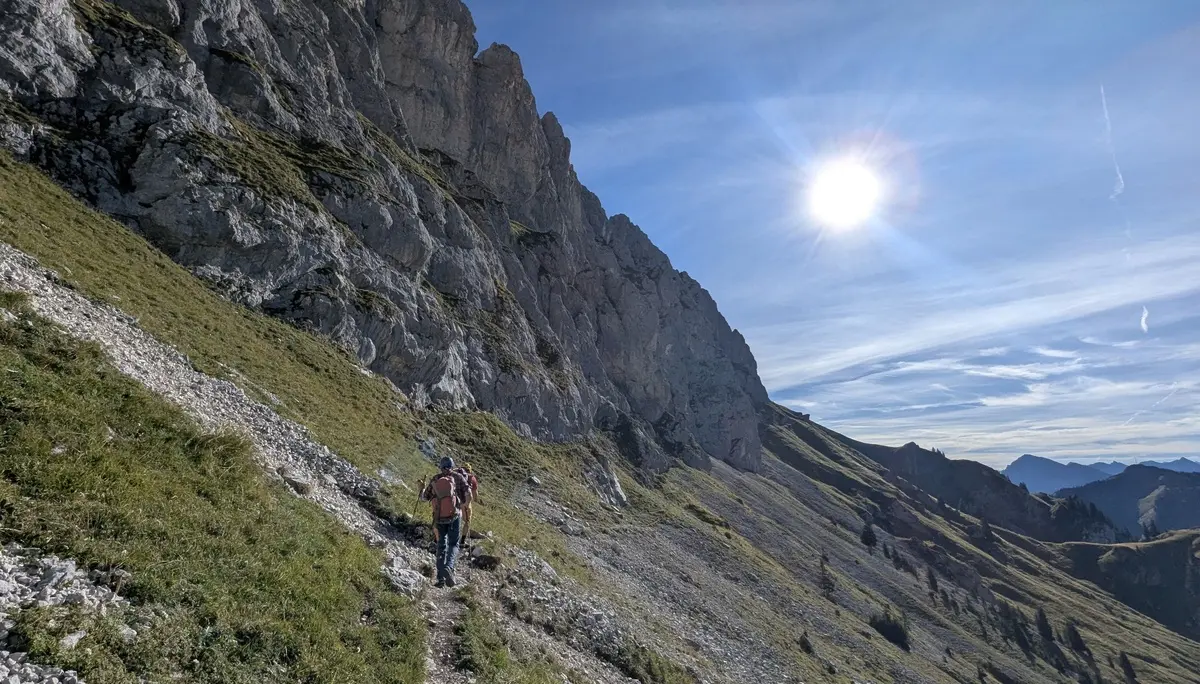 Wanderer mit Rucksack auf schmalem Pfad an steiler, felsiger Bergflanke unter strahlender Sonne | © DAV - FN / Yannic K., Robert H.