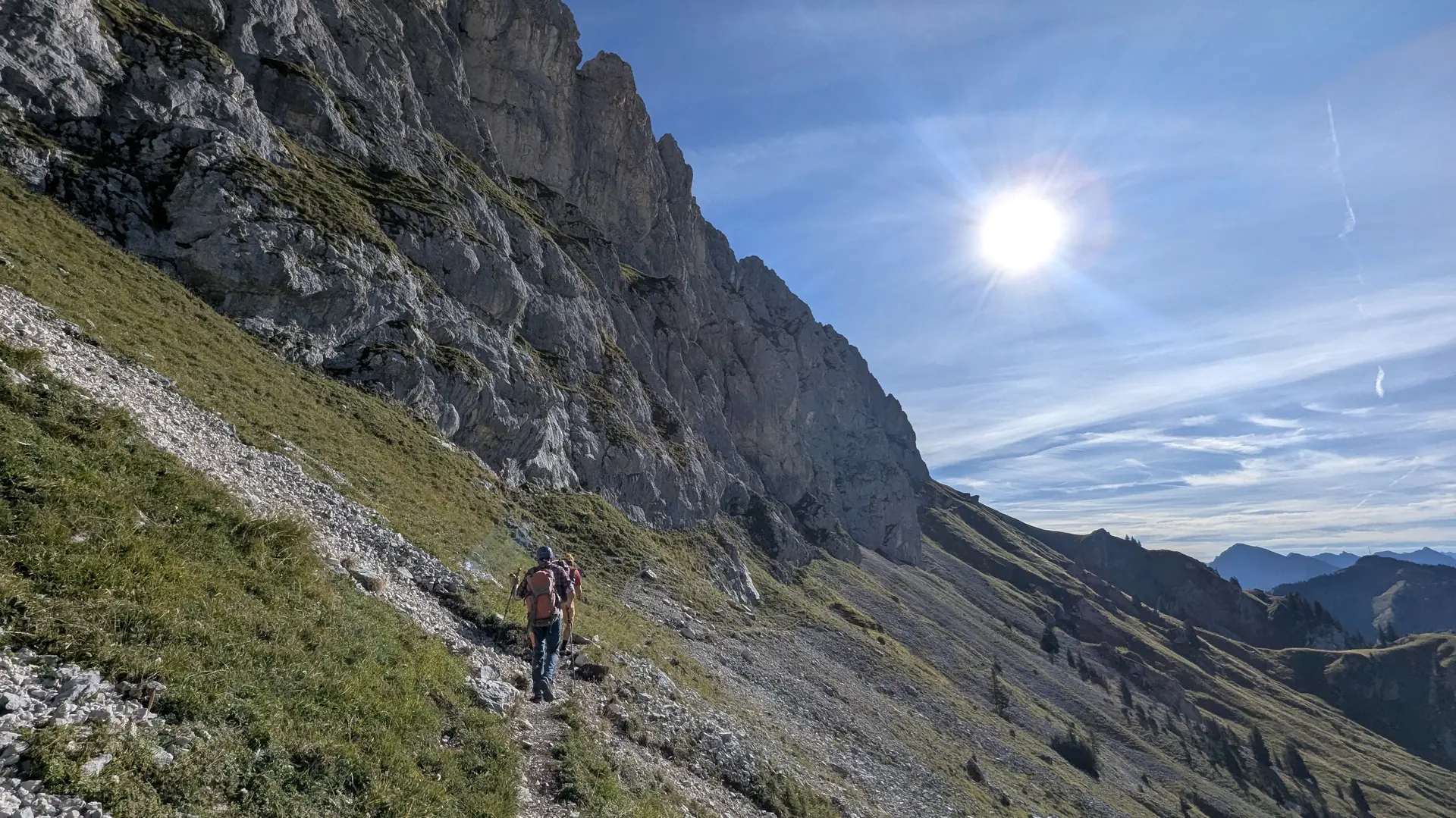 Wanderer mit Rucksack auf schmalem Pfad an steiler, felsiger Bergflanke unter strahlender Sonne | © DAV - FN / Yannic K., Robert H.