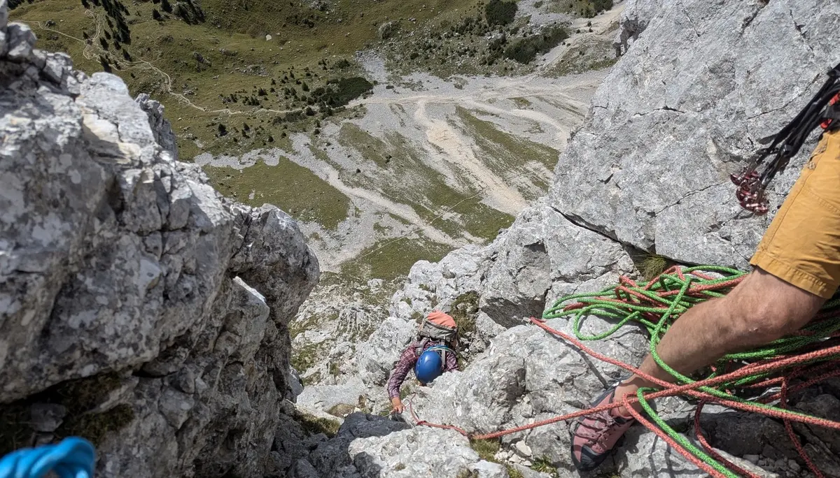 Bergsteiger mit Helm klettert an steiler Felswand, im Vordergrund Seile und ein Arm in gelbem Hemd | © DAV - FN / Yannic K., Robert H.