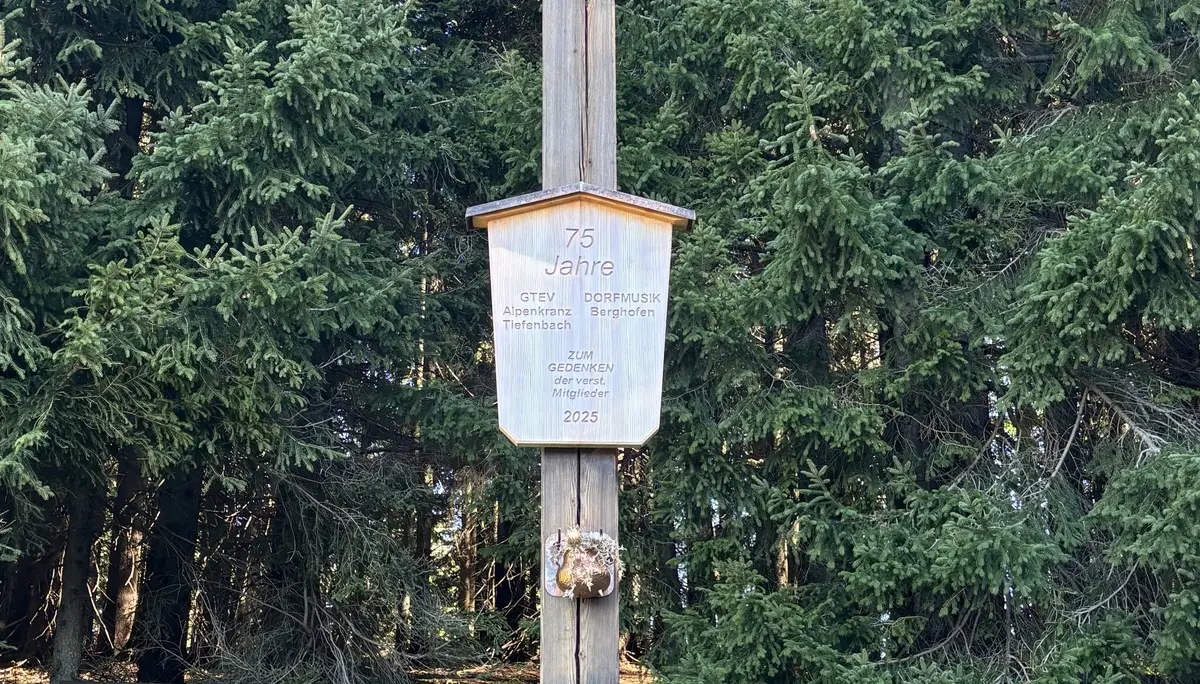 Holzkreuz mit einem Schild und einem Kranz vor einem Wald und einer Bank | © DAV - FN / A. Schech