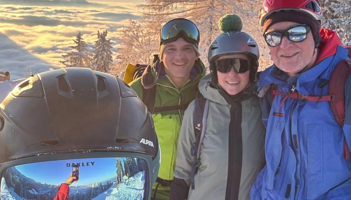 Gruppe von vier Personen mit Helmen und Outdoorbekleidung vor einer verschneiten Berglandschaft mit Baum und Wolkenmeer im Sonnenuntergang | © DAV-FN / Th. Gläser