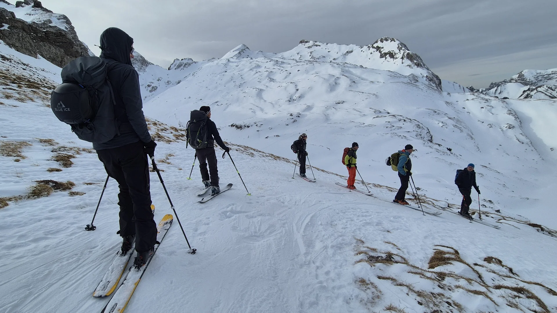 Gruppe von Skifahrern mit Rucksäcken auf schneebedecktem Berghang unter bewölktem Himmel | © DAV-Fn / R. Lebedeff