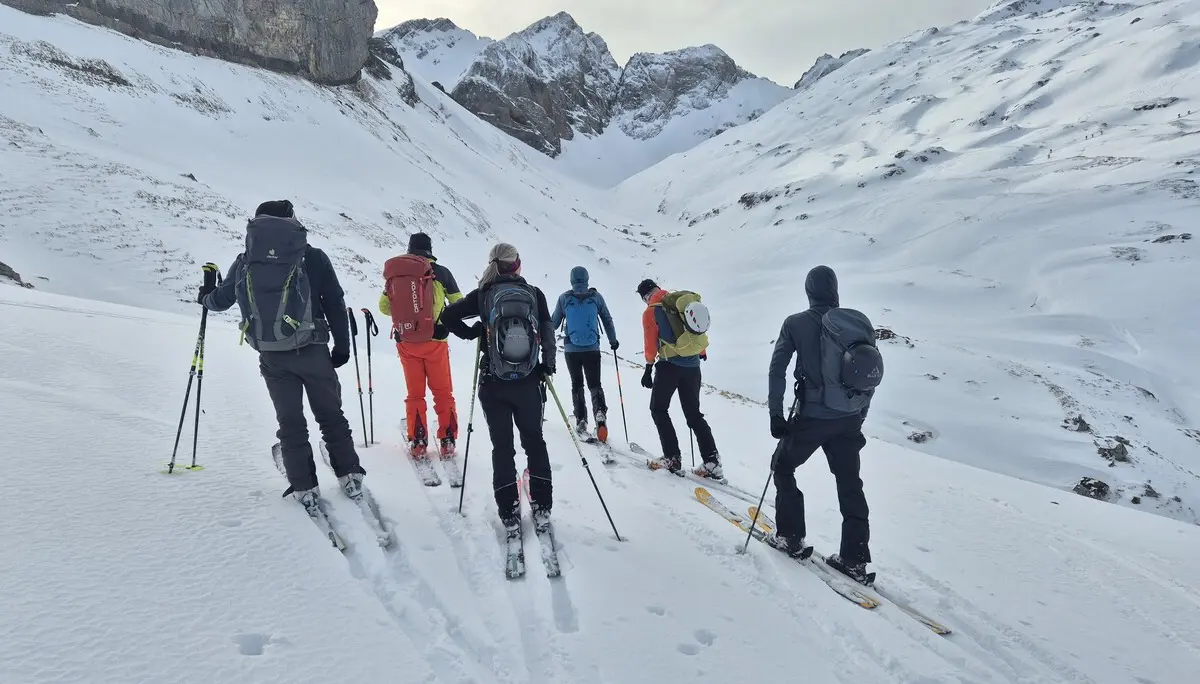 Gruppe von Skifahrern mit Rucksäcken und Skistöcken in verschneiter Berglandschaft | © DAV-Fn / R. Lebedeff