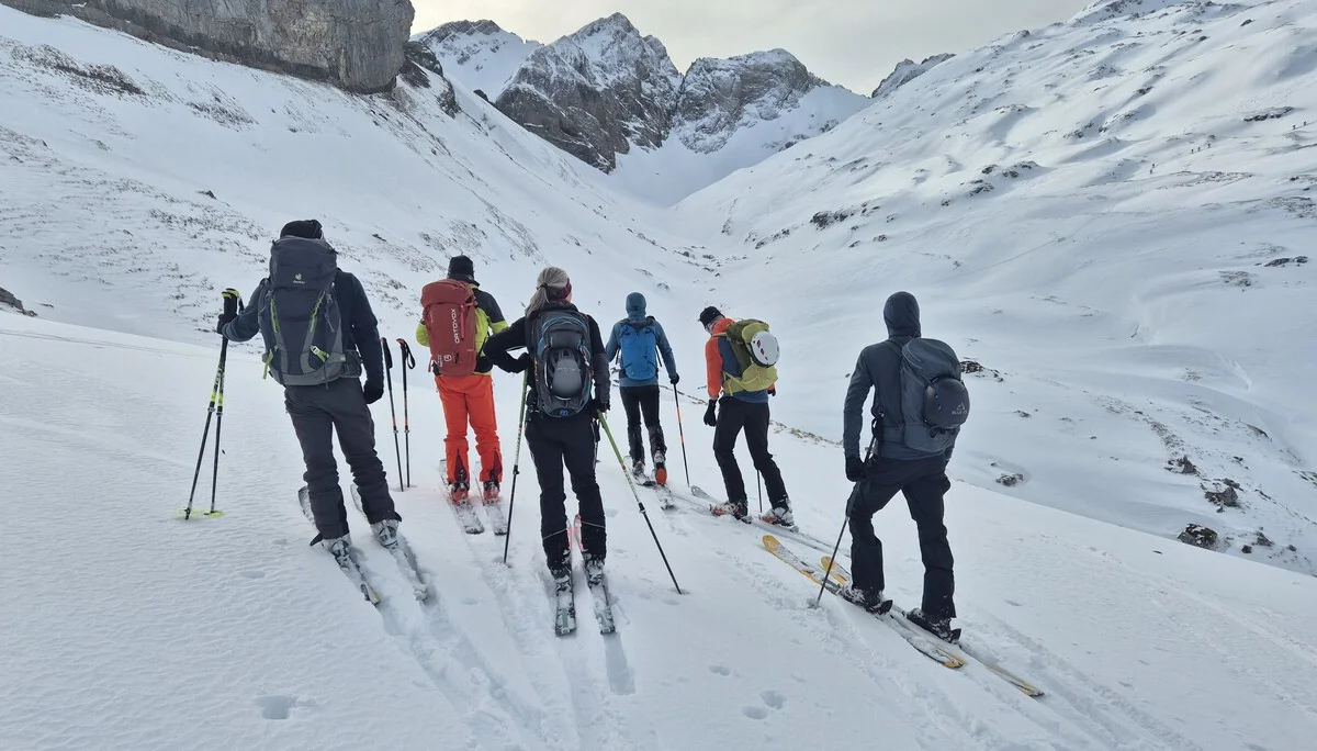 Gruppe von Skifahrern mit Rucksäcken und Skistöcken in verschneiter Berglandschaft | © DAV-Fn / R. Lebedeff