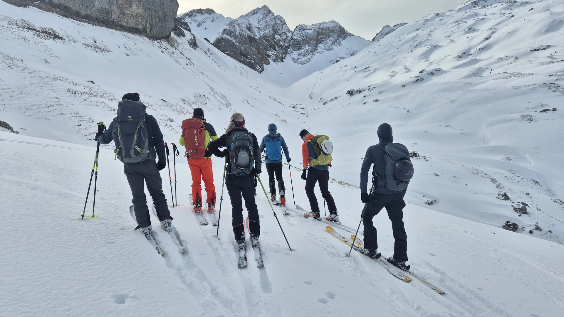 Gruppe von Skifahrern mit Rucksäcken und Skistöcken in verschneiter Berglandschaft | © DAV-Fn / R. Lebedeff