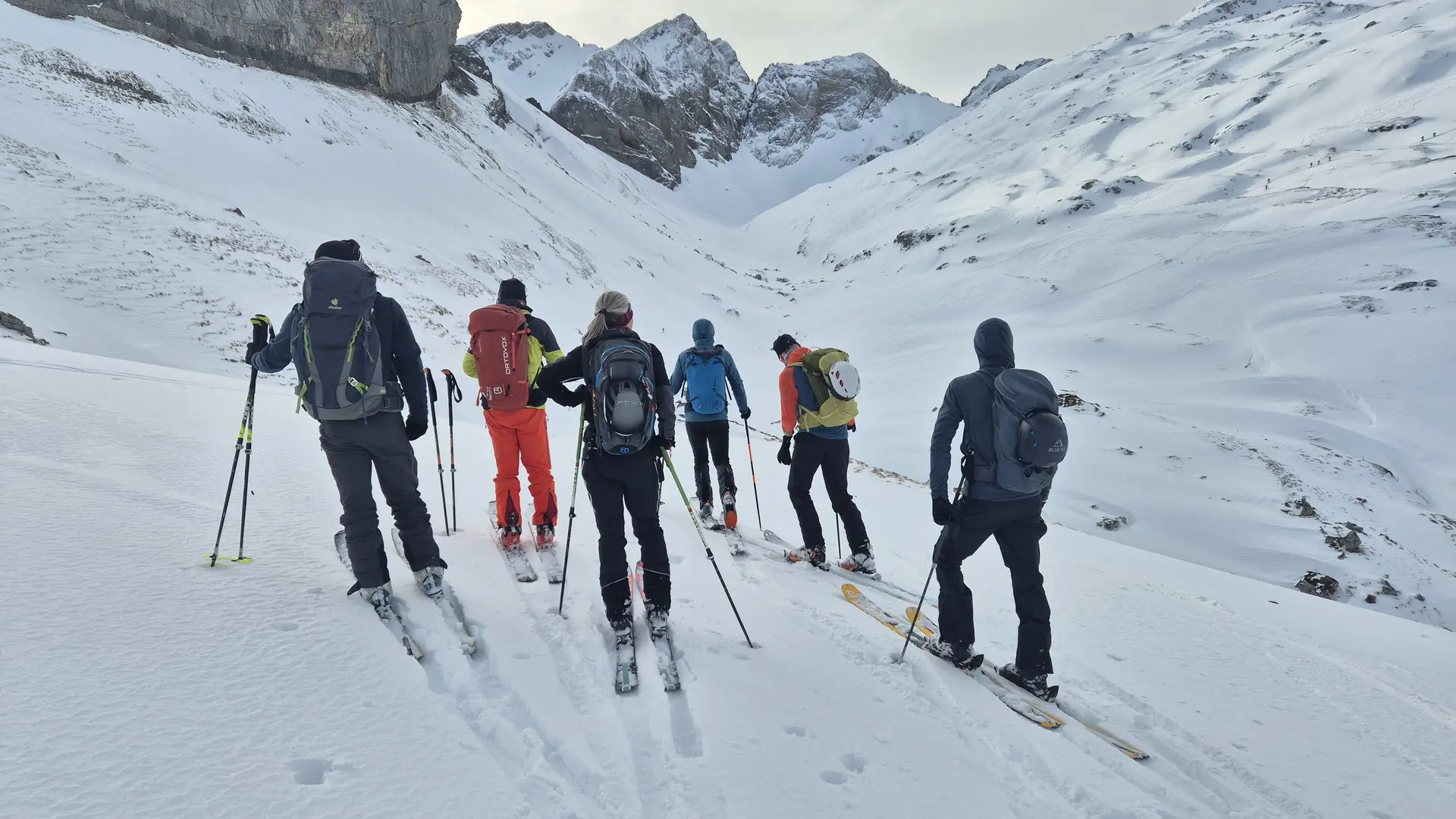 Gruppe von Skifahrern mit Rucksäcken und Skistöcken in verschneiter Berglandschaft | © DAV-Fn / R. Lebedeff
