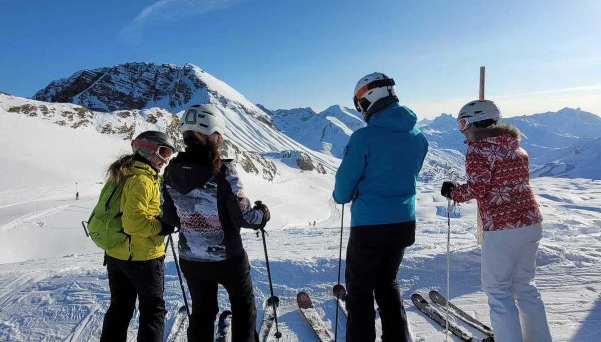Vier Skifahrer mit Helmen und Skistöcken stehen auf schneebedecktem Hang vor Bergpanorama | © DAV-FN / V. u. S. Schmidhuber