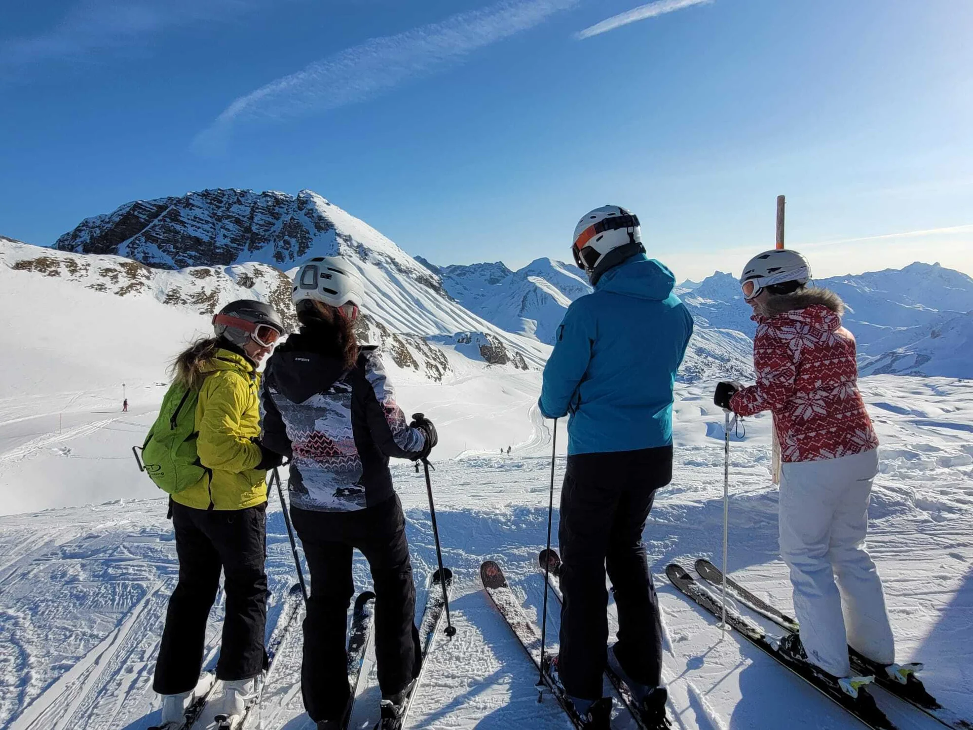 Vier Skifahrer mit Helmen und Skistöcken stehen auf schneebedecktem Hang vor Bergpanorama | © DAV-FN / V. u. S. Schmidhuber