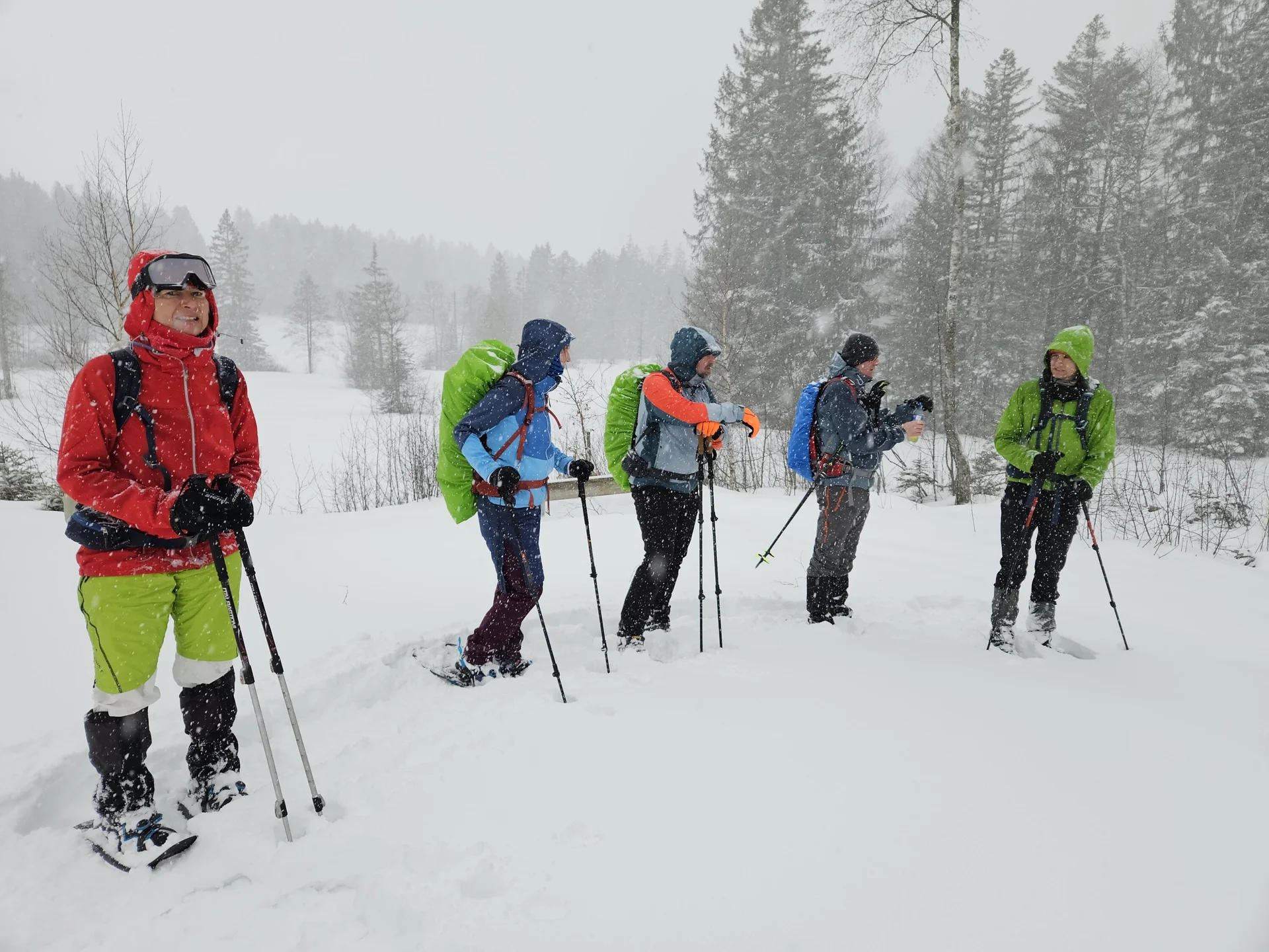 Fünf Personen mit Winterkleidung und Rucksäcken stehen mit Schneeschuhen und Wanderstöcken im tiefen Schnee vor verschneiten Bäumen | © DAV-FN / A. Schababerle