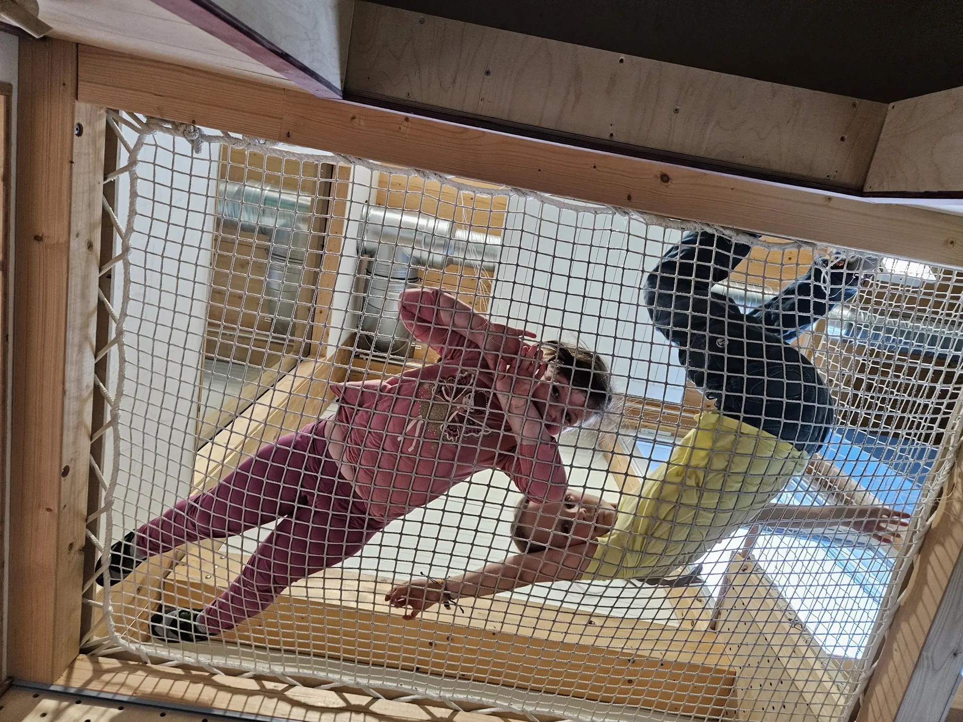 Zwei Kinder liegen auf einem Netz in einem Holzgerüst und schauen nach unten | © DAV-FN / A. Schababerle