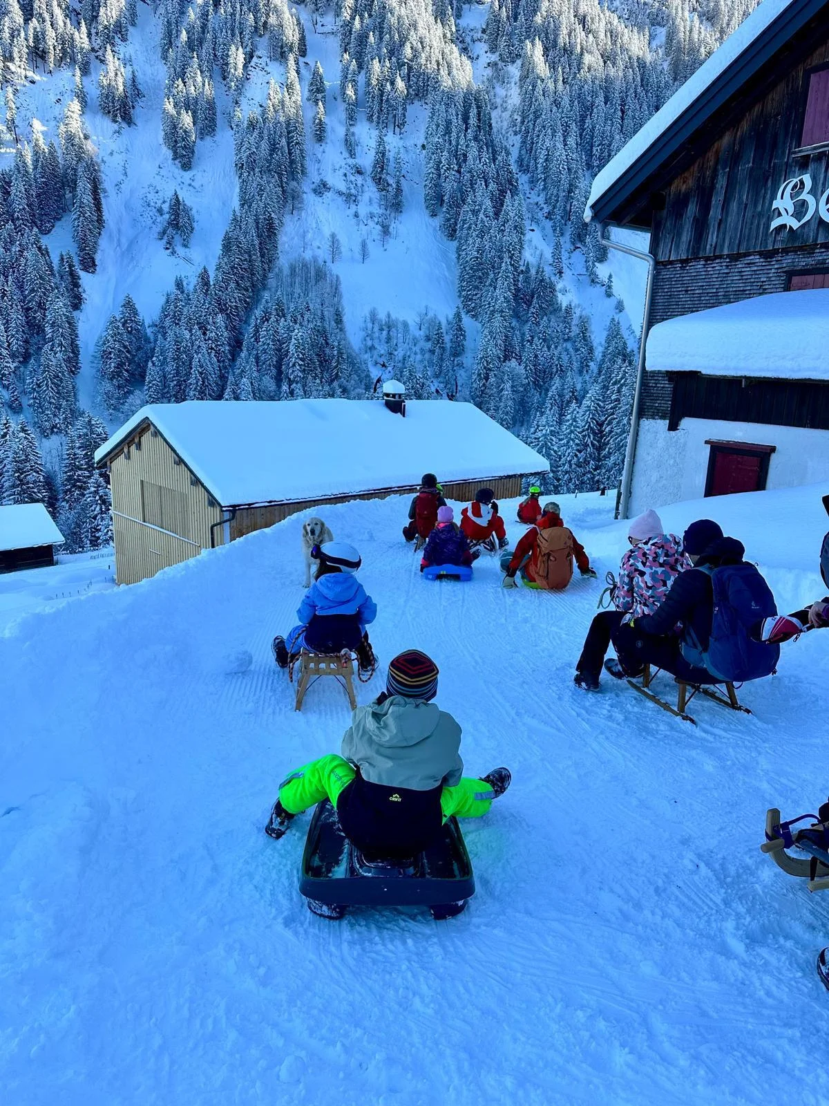 Gruppe von Kindern und Erwachsenen mit Schlitten vor einer Berghütte namens 'Bergkristall' in verschneiter Berglandschaft | © DAV-FN / A. Schababerle