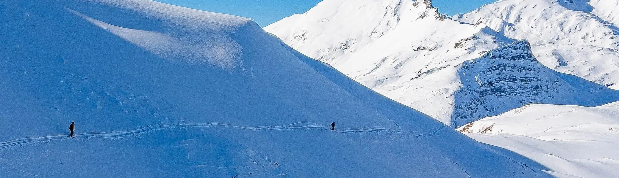 Schneebedeckter Berg mit einzelnen Skifahrern unter blauem Himmel | © DAV-FN / S. Schmidhuber