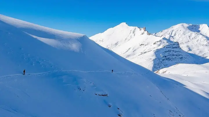 Schneebedeckter Berg mit einzelnen Skifahrern unter blauem Himmel | © DAV-FN / S. Schmidhuber