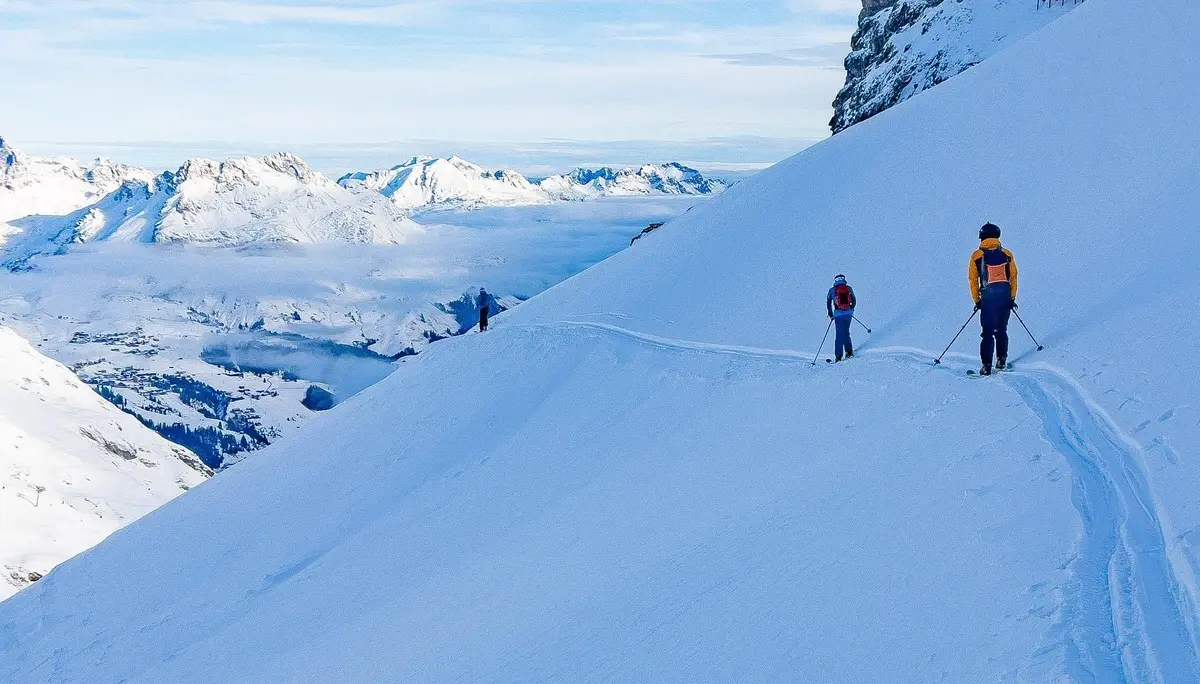 Zwei Skifahrer auf einer schneebedeckten Bergpiste mit Bergpanorama und blauem Himmel | © DAV-FN / S. Schmidhuber