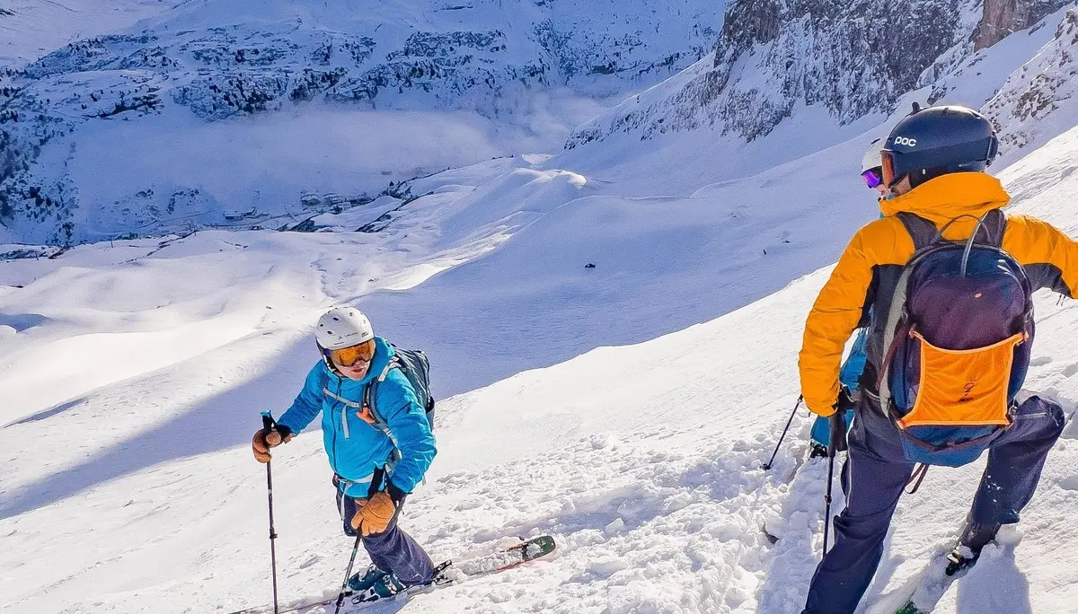 Zwei Skifahrer in bunter Winterkleidung auf schneebedecktem Hang vor Bergpanorama unter bewölktem Himmel | © DAV-FN / S. Schmidhuber