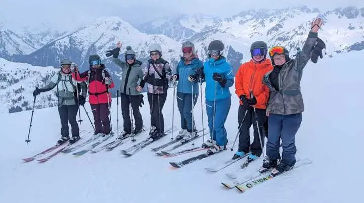 Gruppe von Skifahrern in Winterkleidung mit Skistöcken auf schneebedecktem Berg vor Bergpanorama | © DAV-FN / V. Schmidhuber