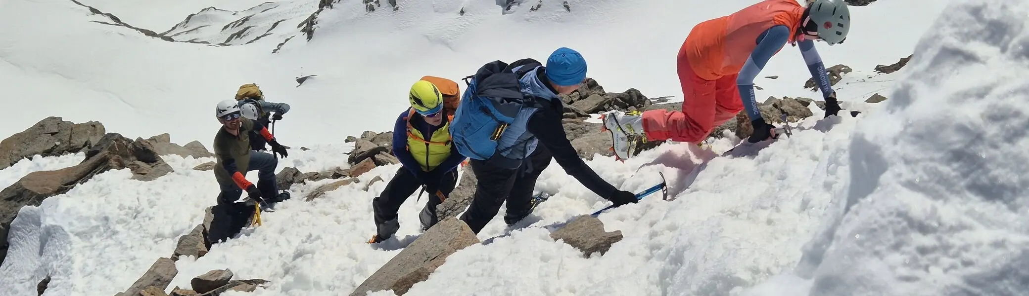 Gruppe von Bergsteigern mit Helmen und Rucksäcken klettert steilen schneebedeckten Hang hinauf | © DAV-FN / R. Lebedeff