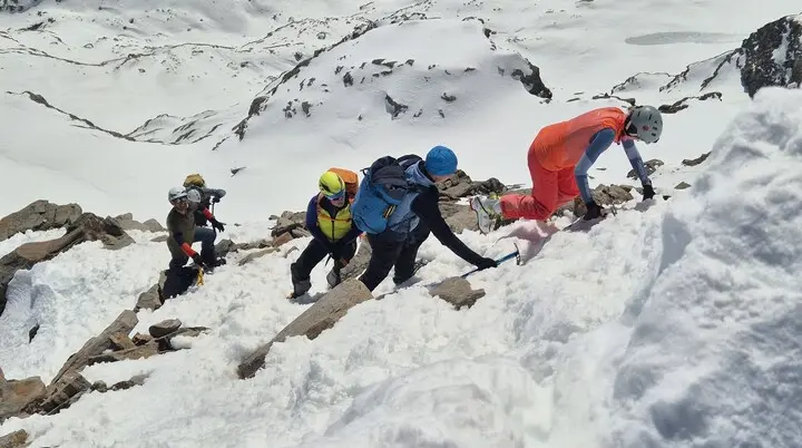 Gruppe von Bergsteigern mit Helmen und Rucksäcken klettert steilen schneebedeckten Hang hinauf | © DAV-FN / R. Lebedeff
