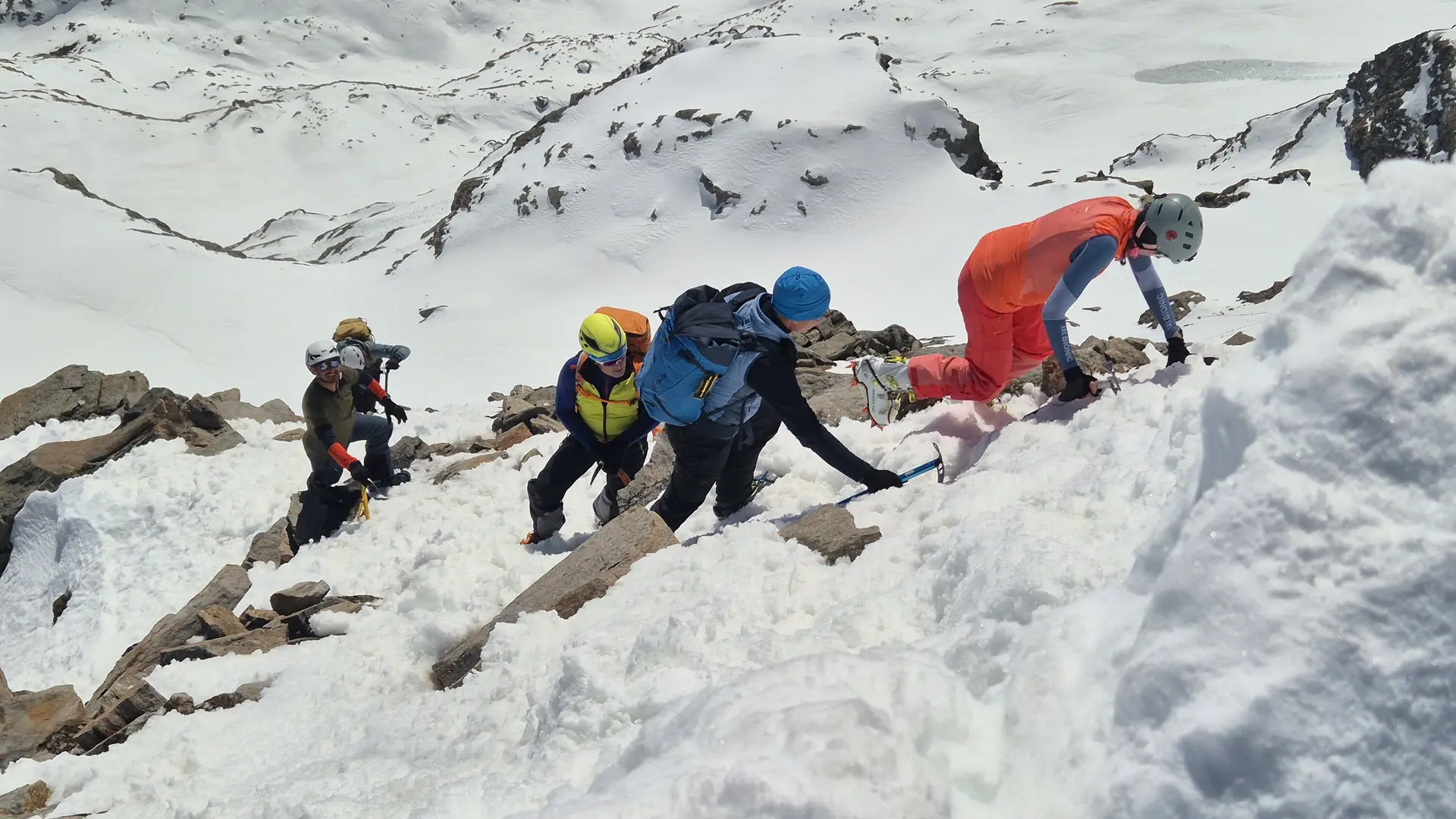 Gruppe von Bergsteigern mit Helmen und Rucksäcken klettert steilen schneebedeckten Hang hinauf | © DAV-FN / R. Lebedeff