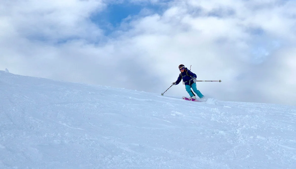 Skifahrer in blauer Hose und dunkler Jacke fährt auf schneebedecktem Hang unter bewölktem Himmel | © DAV/Dirk Amos