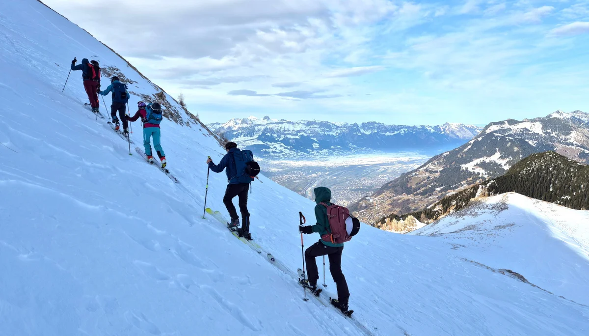 Gruppe von vier Personen mit Rucksäcken und Wanderstöcken steigt schräg einen schneebedeckten Hang in den Bergen hinauf | © DAV/Dirk Amos
