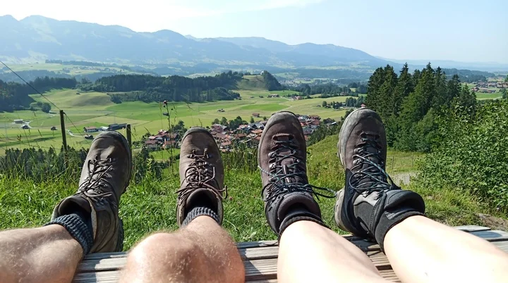 Zwei paar Füsse mit Bergstiefel mit weiter Sicht in ein Allgäuer Tal  | © DAV-FN