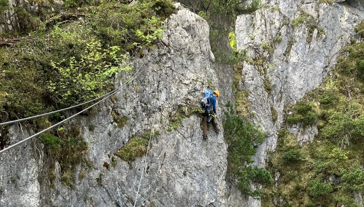 Zwei Kletterer an steiler Felswand mit Sicherungsseilen und umgeben von Vegetation | © DAV-FN / L. Fischer
