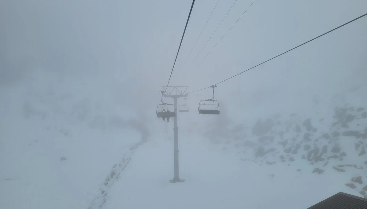 Leere Skilift-Sessel hängen an Seilen über schneebedecktem, nebligem Berggelände | © DAV-FN / C. Erbelding