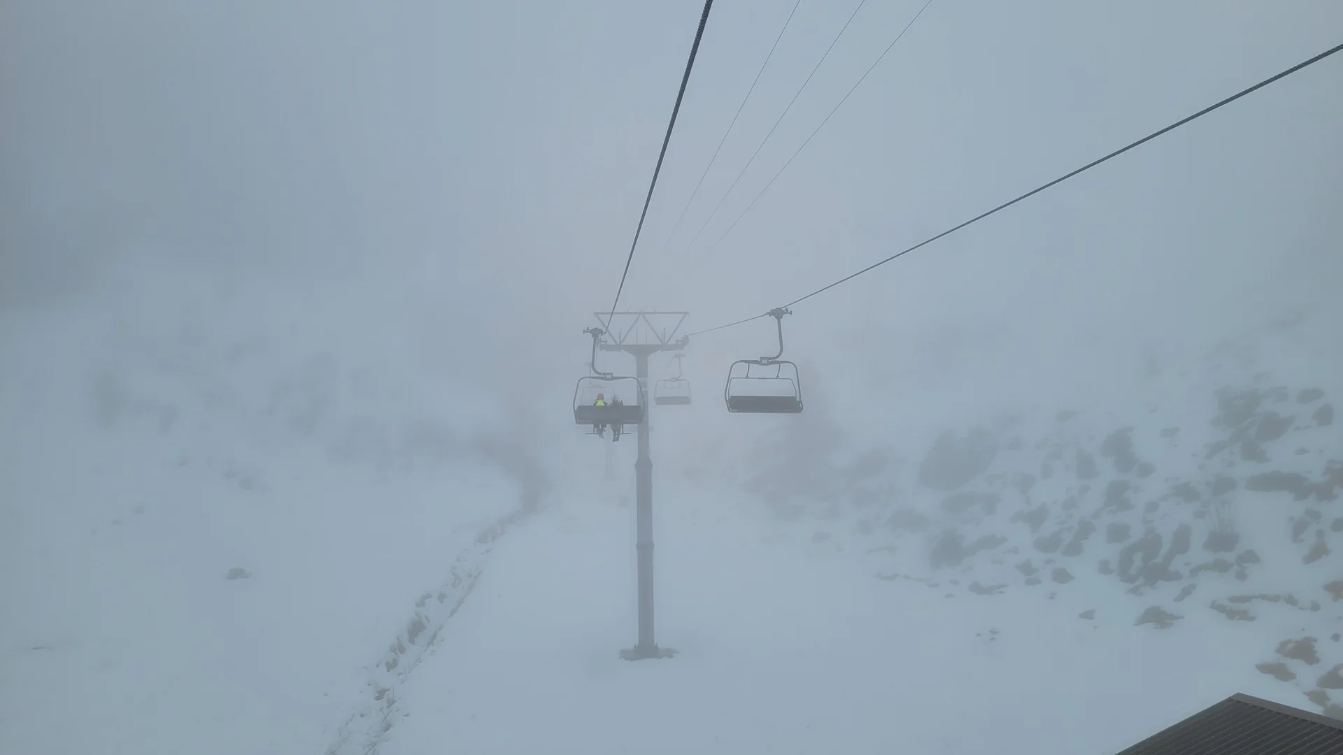 Leere Skilift-Sessel hängen an Seilen über schneebedecktem, nebligem Berggelände | © DAV-FN / C. Erbelding