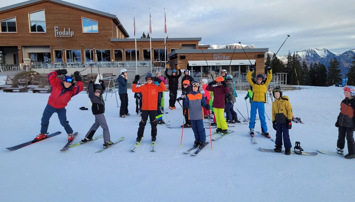 Gruppe von Skifahrern in bunter Winterkleidung vor einem Holzgebäude mit 'Prodalp' und Bergen im Hintergrund | © DAV-FN / C. Erbelding
